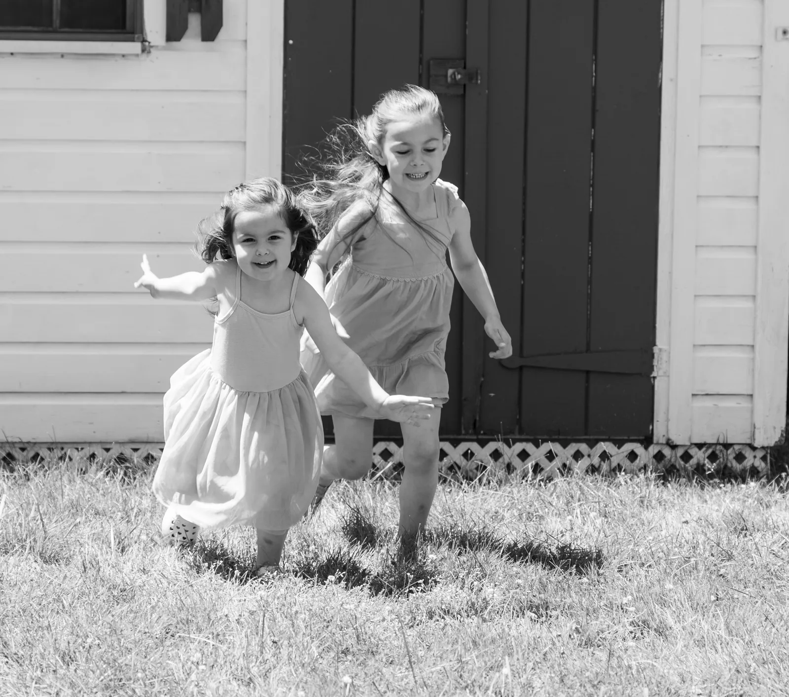Two young sisters running across a lawn